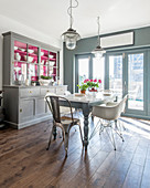 Kitchen dresser with hot-pink cupboard interiors in sunny dining room in shades of grey