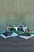 Green cushions on floor around low table with place settings