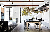 Kücheninsel aus schwarzem Granit, Esstisch und Klassikerstühle in offenem Wohnraum