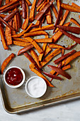 Sweet potato chips with two dips on a baking tray (seen from above)