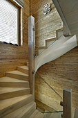 Staircase with glass balustrade in chalet with wood-panelled walls