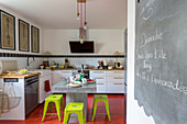 Concrete table and bright green stools in front of L-shaped kitchen counter