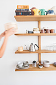 Hands removing item from shelves of crockery and kitchen utensils