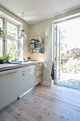 Pale wooden flooring in light-flooded kitchen with garden access