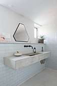 Concrete washstand in purist bathroom with small window