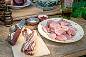 Schweinefleisch und Speck mit Gewürzen und Öl auf Holztisch