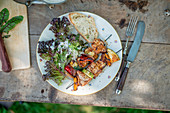 Grilled meat and vegetable skewers with salad and bread