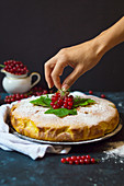 A woman's hand decorating red currant cake