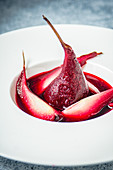 Red wine infused pears on a white plate