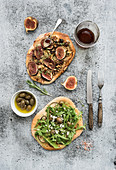 Rustic homemade pizzas with eggpant, cheese, olives, arugula, prosciutto and figs over grunge backdrop