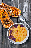 Cream of pumpkin soup with breadcrumbs and edible flowers, and oven-baked pumpkin with thyme and garlic