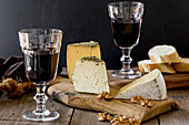 A cheese platter with bread, walnuts and red wine
