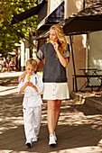 A little boy wearing a karate suit with his mother wearing a black blouse and a white skirt eating ice cream