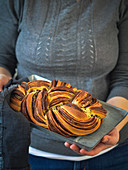 A woman holding a plaited bread with chocolate and cinnamon