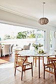 Round table with classic chairs next to open terrace doors