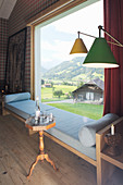 Elegantes Wohnzimmer mit gepolsterter Sitzbank vor Panoramafenster mit Landschaftsblick