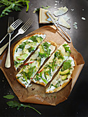 Pizza bread with cream cheese, avocado, rocket and Parmesan