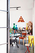 Dog under table with wrought iron table frame, low bookcase in background