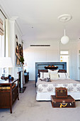 Double bed with blue lacquered shelf at the head end in front of the built-in wardrobe, suitcase at the end of the bed