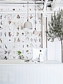 Botanische Karten an der Wand, Olivenbäumchen und weißer Schreibtisch