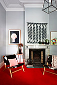 Two chairs on red carpet in front of fireplace in living room with light gray walls and stucco