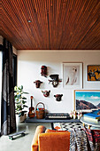 Mask collection, pictures, cones and musical instruments, in the foreground coffee table and leather couch in the living room