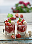 Vegan coconut and strawberry dessert in glasses with coconut balls and fresh berries