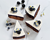 Vegan chocolate and blueberry cake with a cream cheese topping and fresh berries