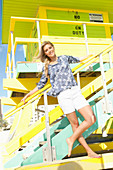 A blonde woman wearing shorts and a floral tunic outside a beach house