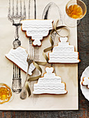 Kekse in Form von Hochzeitstorten mit weisser Zuckerglasur