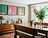 Three artworks on wall above retro sideboard in dining room