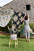 Frau im Blümchenkleid bei Wäscheaufhängen im Garten