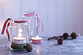 Selbstgestaltete weihnachtliche Windlichter mit Moos, Teelicht und Schleifenband