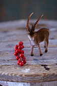 Steinbock-Figur und roter Beerenzweig als rustikal winterliche Dekoration