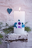 White pillar candle festively decorated with ribbon and star