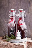 Glühweinsirup in Bügelflaschen weihnachtlich dekoriert mit Vogelfedern