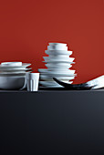 Stacked crockery, beaker and horn against red background