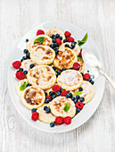 Syrniki (cottage cheese pancakes) with fresh forest berries and sour cream sauce