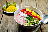 Breakfast bowl mit Erdbeersmoothie, Kiwi, Kokosflocken, Erdbeeren, Mango und Chiasamen