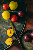 Colourful plums on a rusty metal platter with a rusty knife