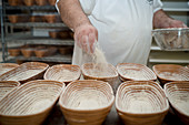 Bäcker bemehlt Brotkörbe in der Backstube