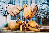 A man peeling fresh sweet potatoes