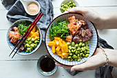 Poke bowls with tuna, salmon, edamame, mango and wakame salad