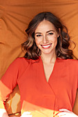 Woman with brown hair wearing orange blouse