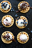 Waffles topped with vanilla, strawberry and chocolate ice cream, melted chocolate, frozen berries and chocolate chips