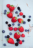 Strawberries, raspberries, blueberries and blackberries on a mint coloured tray