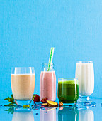 Vier verschiedene Smoothies vor blauem Hintergrund