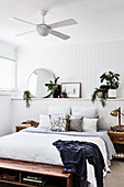 Doppelbett an Wandvorsprung mit Holzverkleidung und Deckenventilator in weißem Schlafzimmer