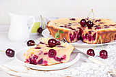 Sweet cherry clafouti and piece of cake on wihite saucer