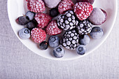 Frozen berries in frost (raspberries, blackberries, blueberries) on white plate